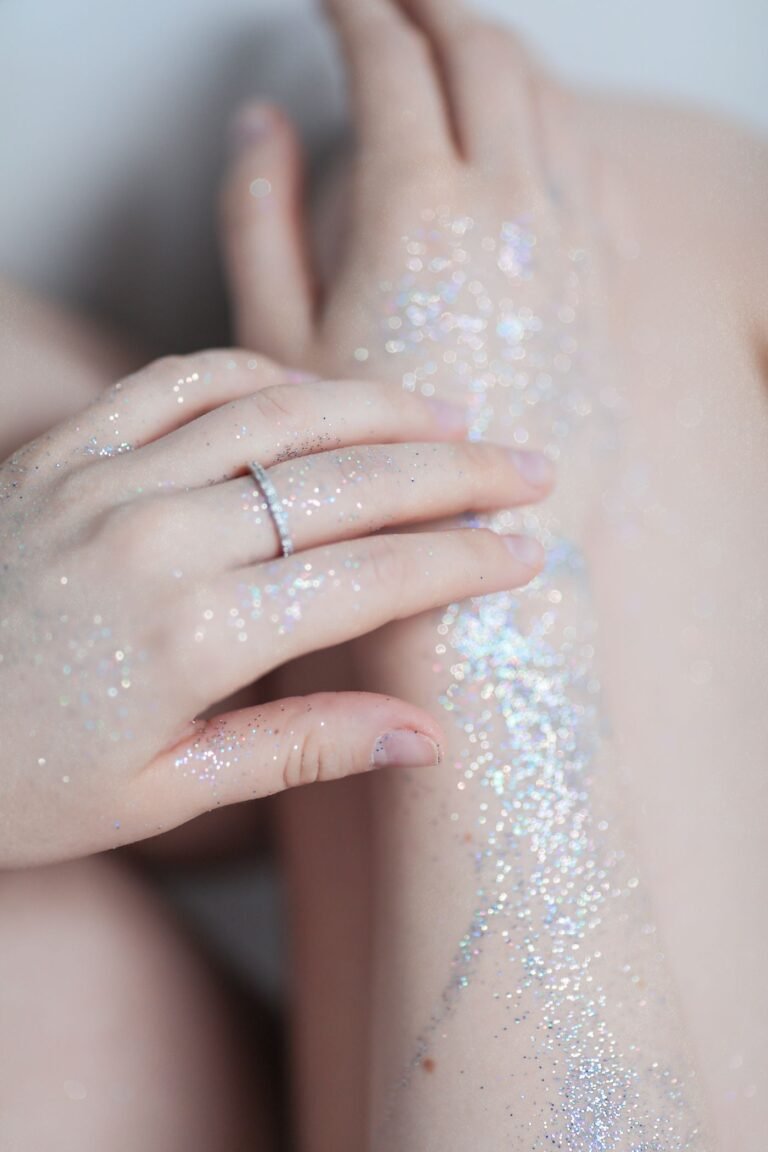 Mano tocando piel con destellos de glitter